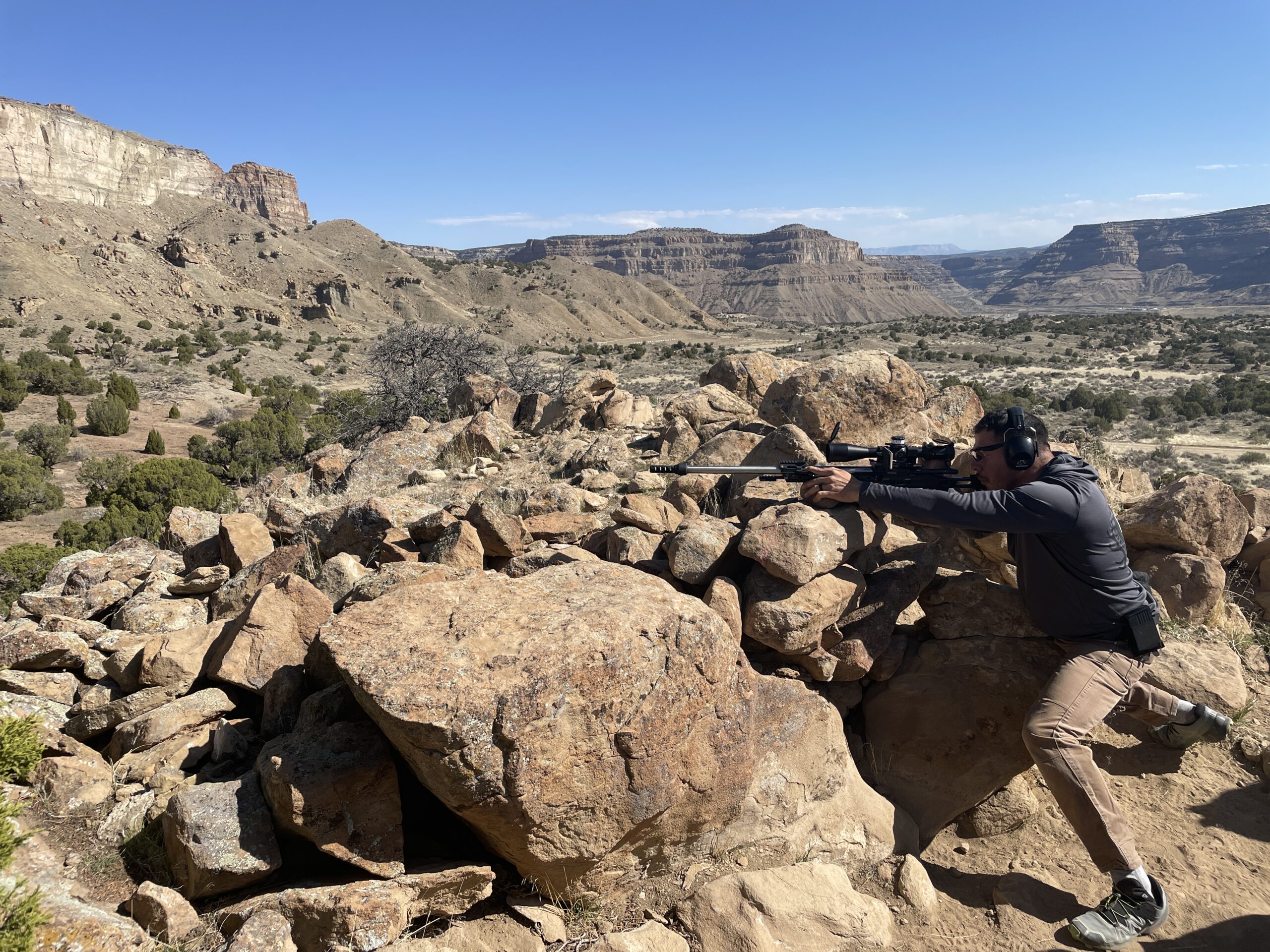 Shooter using a precision rifle from a rocky field position
