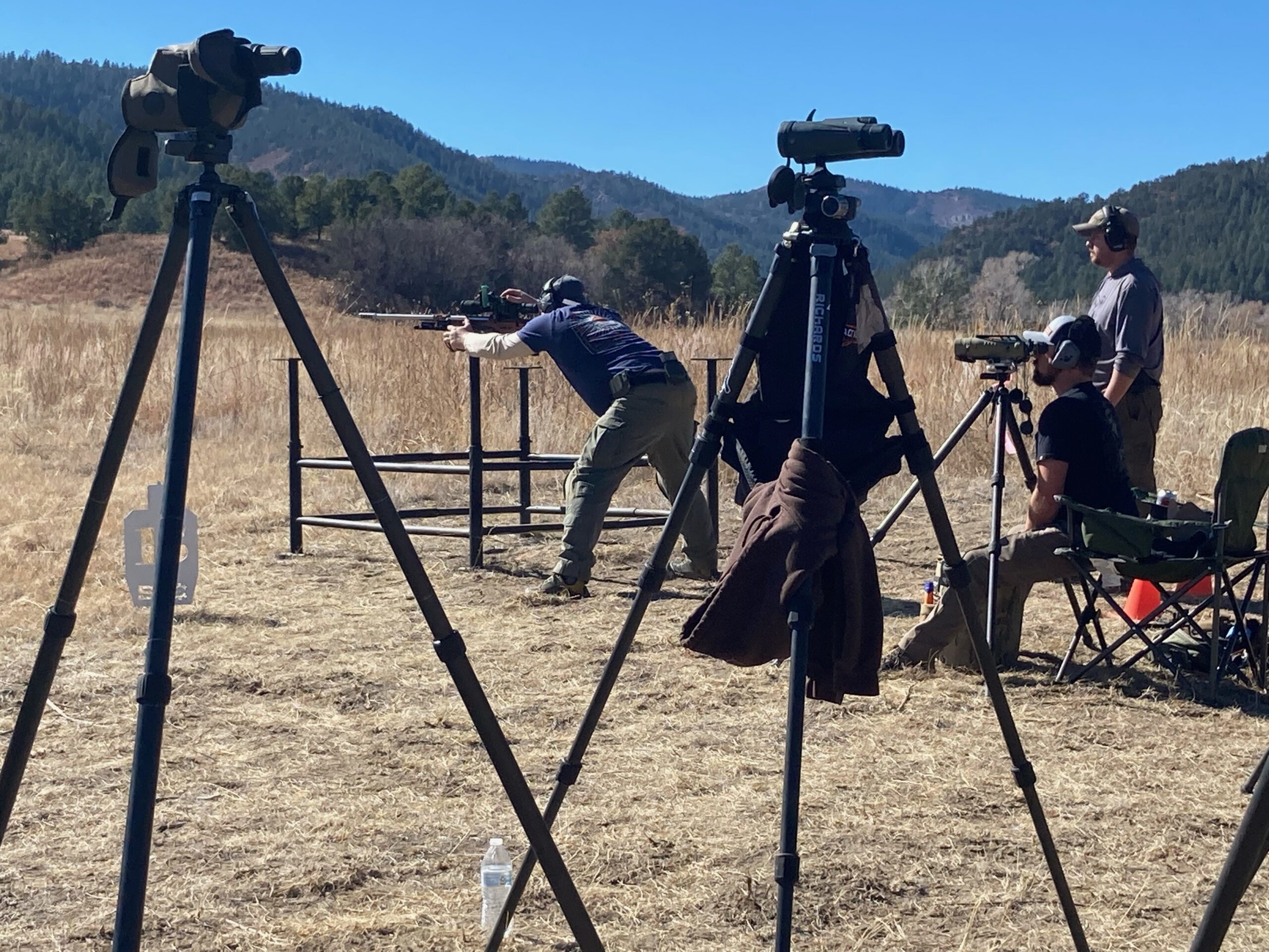 Precision rifle competitors and spotting equipment on an outdoor range
